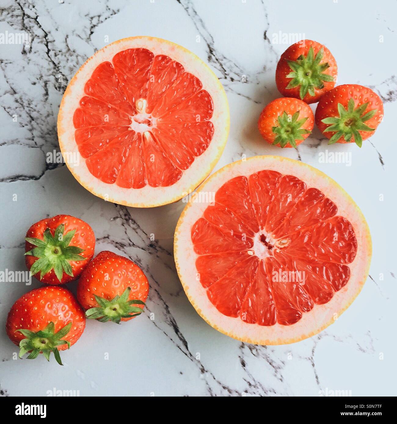 Fresh red grapefruit surrounded by strawberries - Smartphone Captured Stock Image