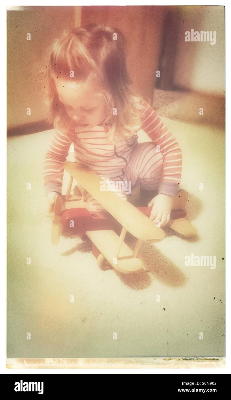 Little girl playing with an old wooden airplane Stock Photo
