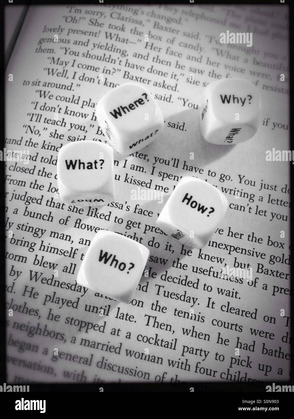 A couple of dice with question words on the page of an open book - Smartphone Captured Stock Image