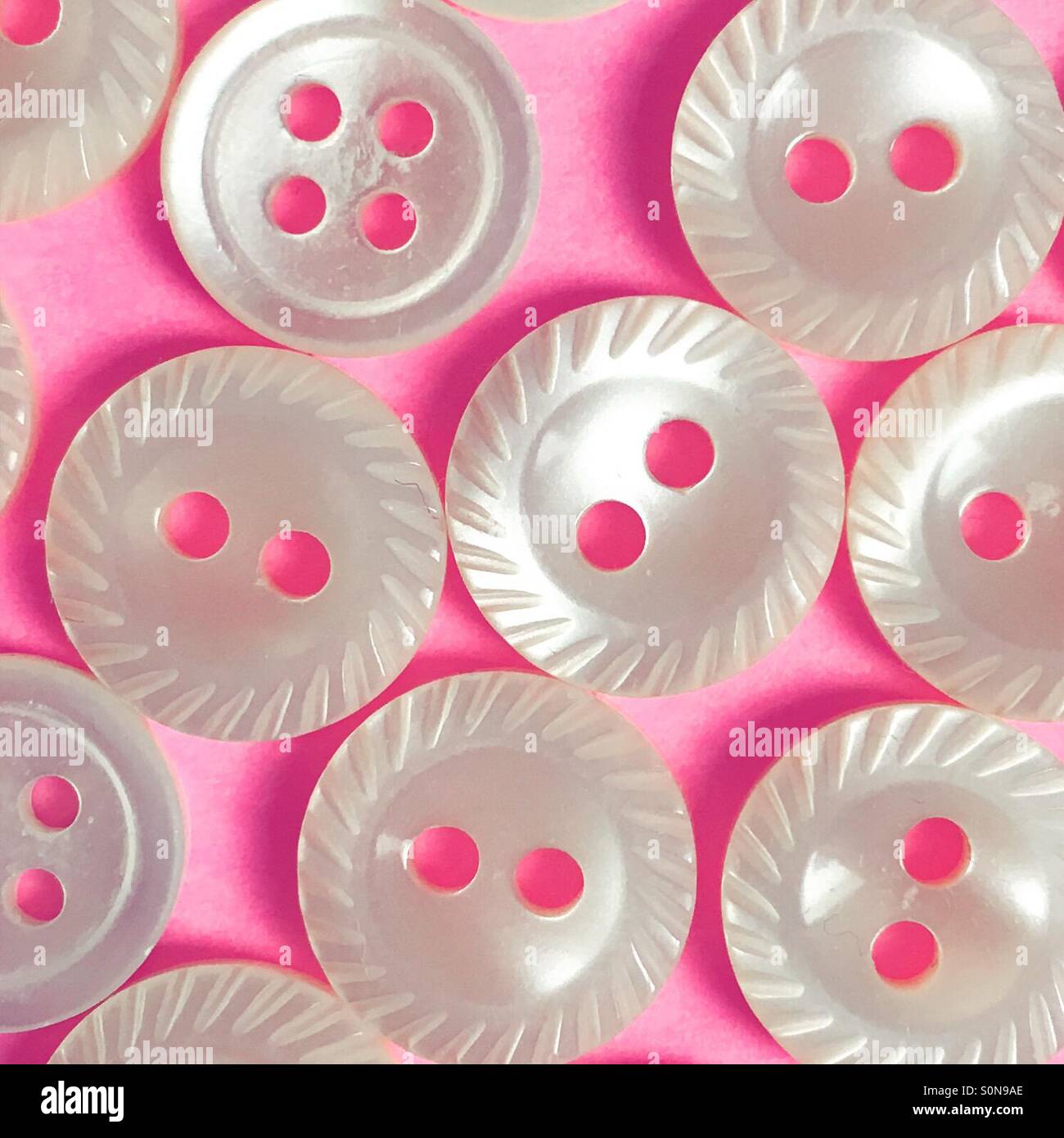 White milled edge buttons on a pink background Stock Photo - Alamy