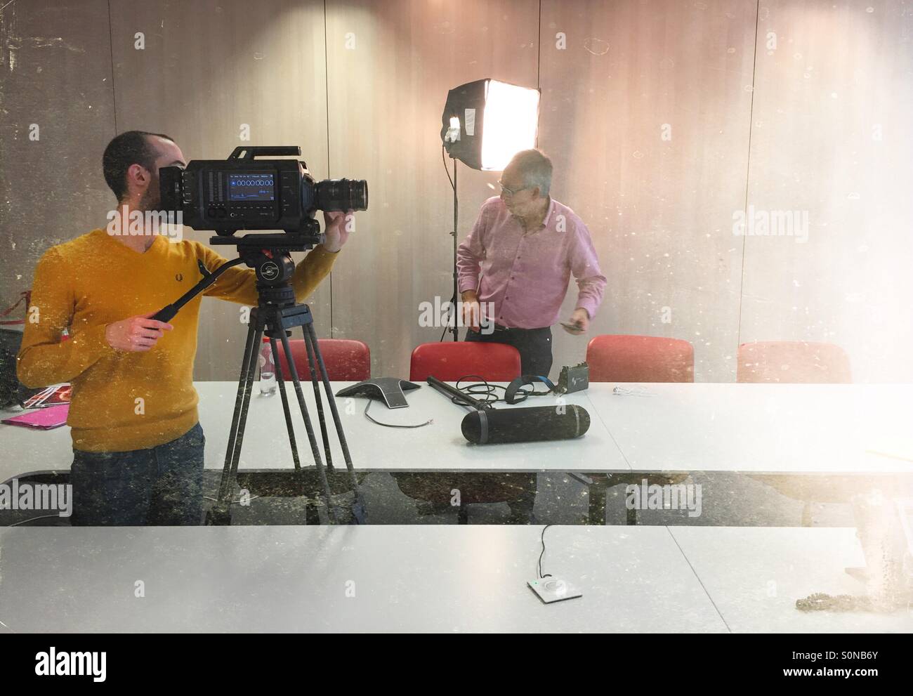 Camera crew preparing to shoot an interview inside an office meeting room. - Smartphone Captured Stock Image