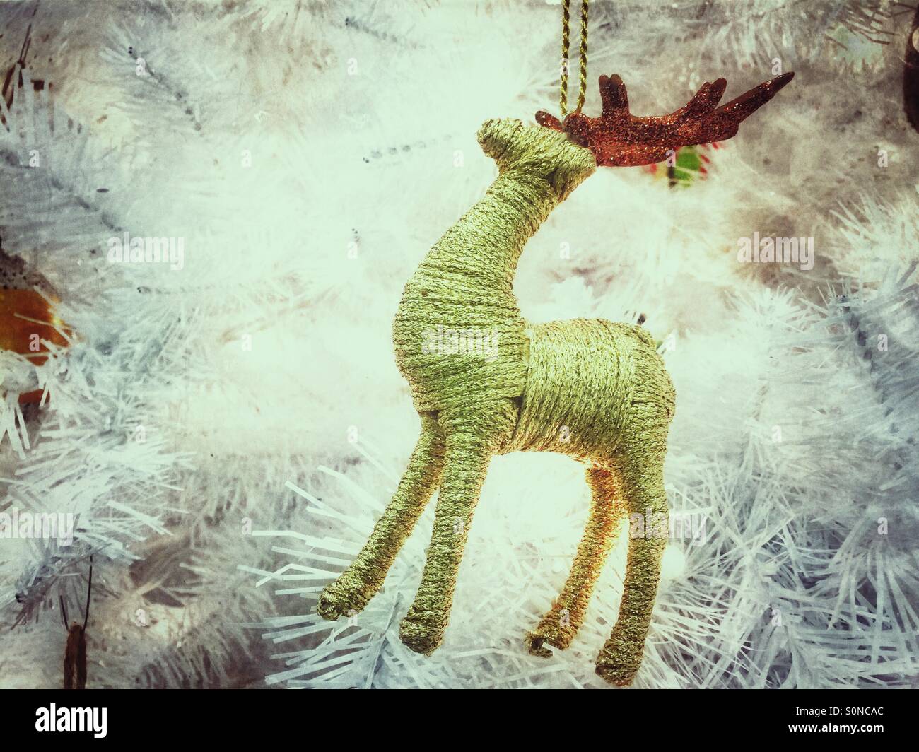 Gold yarn reindeer Christmas tree ornament on white tree - Smartphone Captured Stock Image