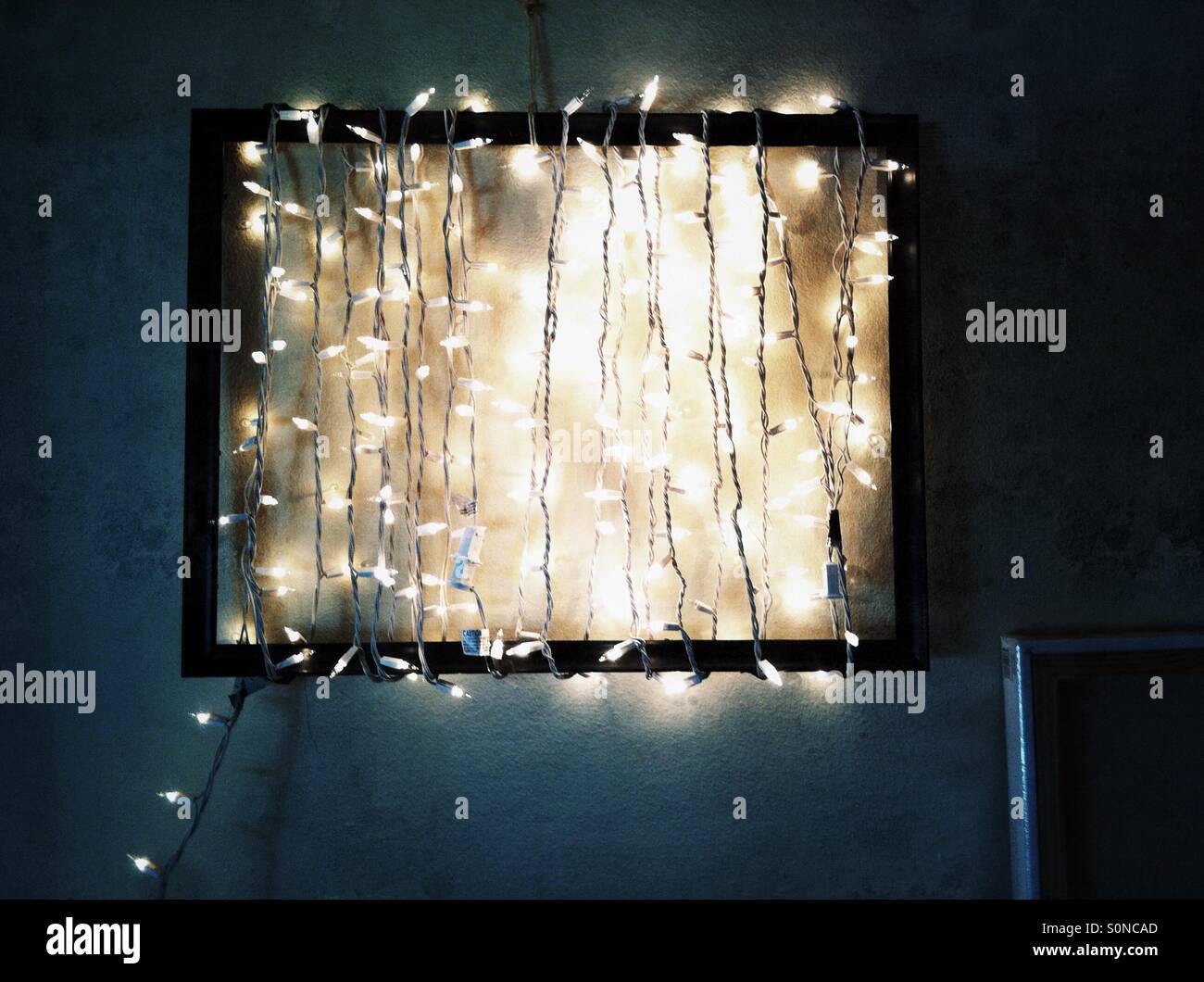 string of white Holiday lights wrapped around empty black picture frame - Smartphone Captured Stock Image