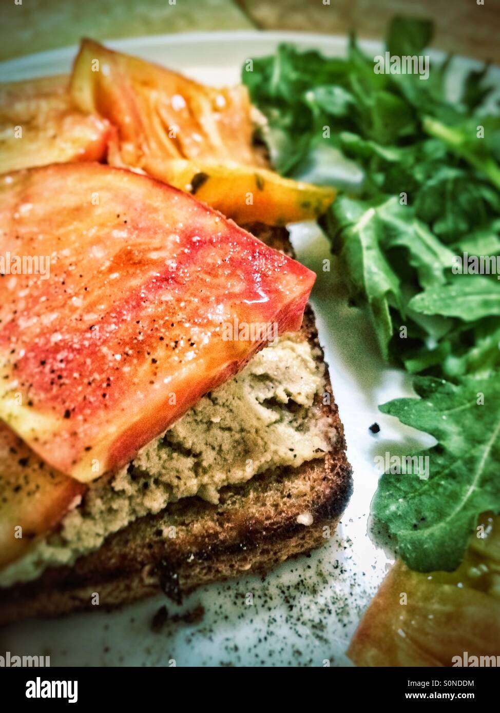 Heirloom tomatoes and hummus on whole grain toast Stock Photo
