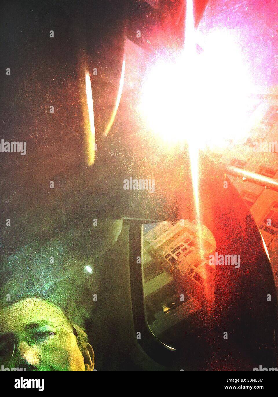 Man in a car during the night with houses and streetlight in the background. - Smartphone Captured Stock Image