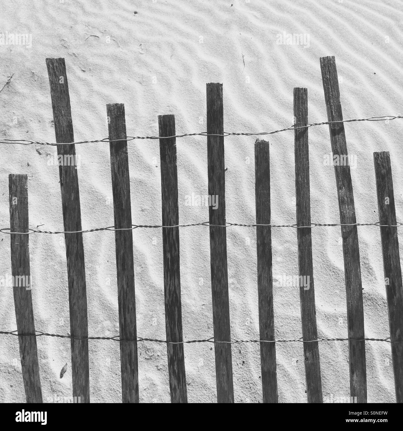 Sand dune with fence and patterns in the sand, Florida, USA. - Smartphone Captured Stock Image