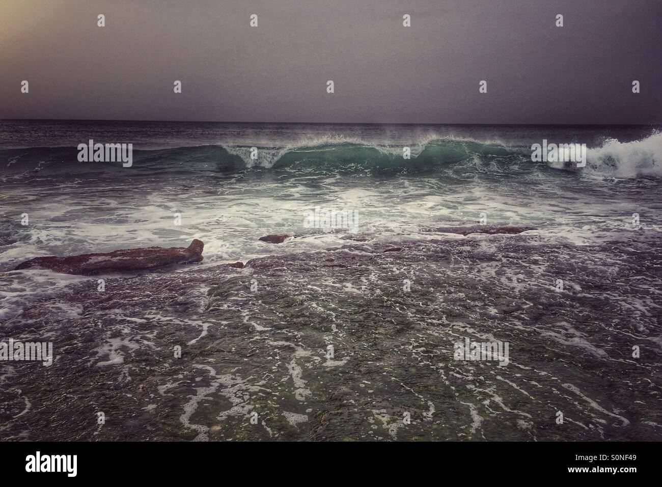 Waves breaking over rocks with sun to the left - Smartphone Captured Stock Image