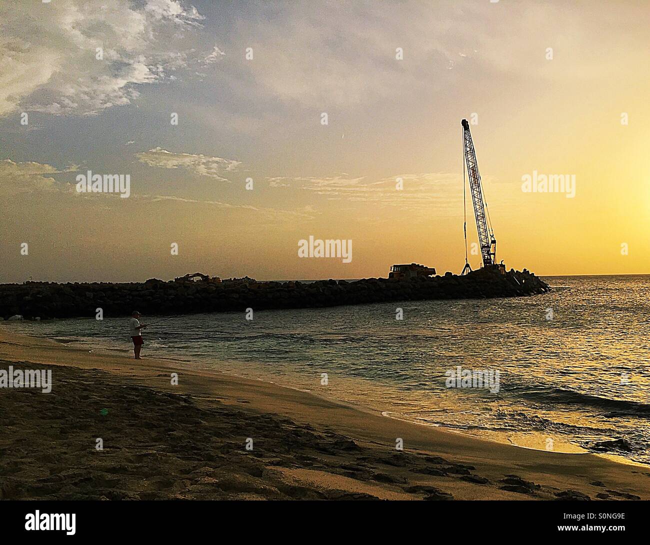 Man fishing at sunset with crane on a pier Cape Verde - Smartphone Captured Stock Image