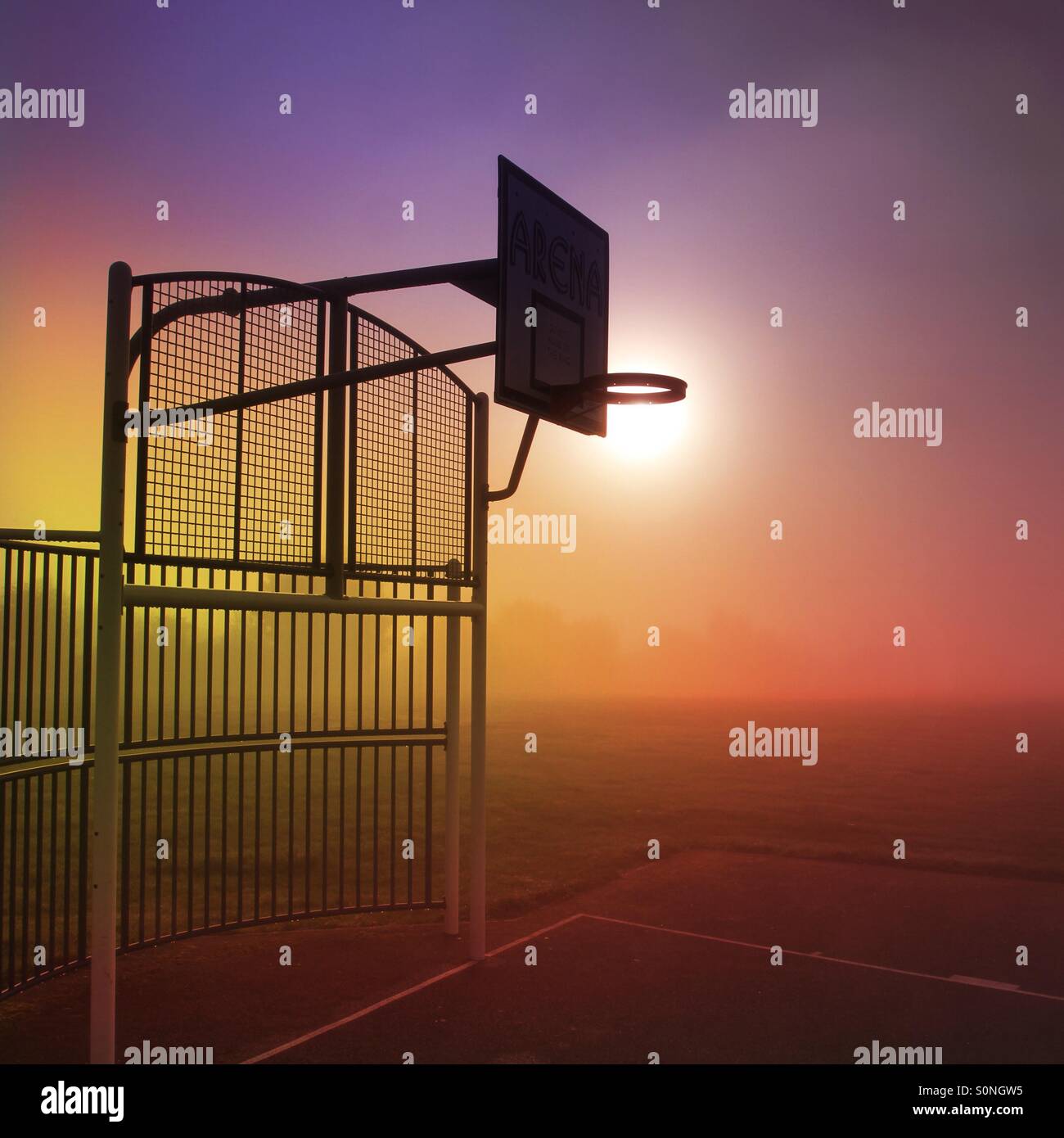 An outdoor basketball hoop on a colourful, misty morning just waiting for a player to use it. Stock Photo