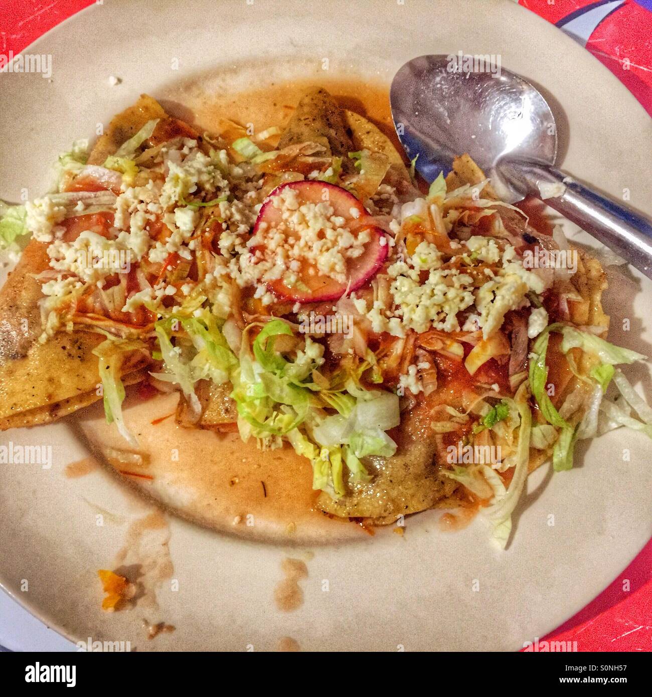 Three tacos topped with shredded lettuce, radish slices, and cotija