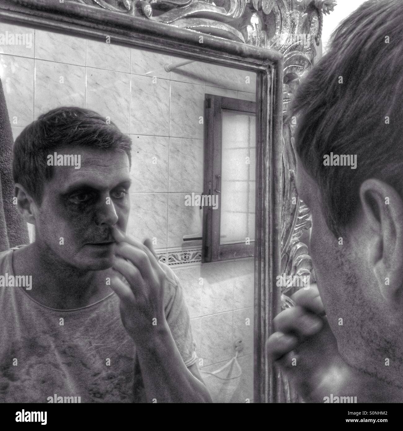 Man putting on make up in mirror Stock Photo