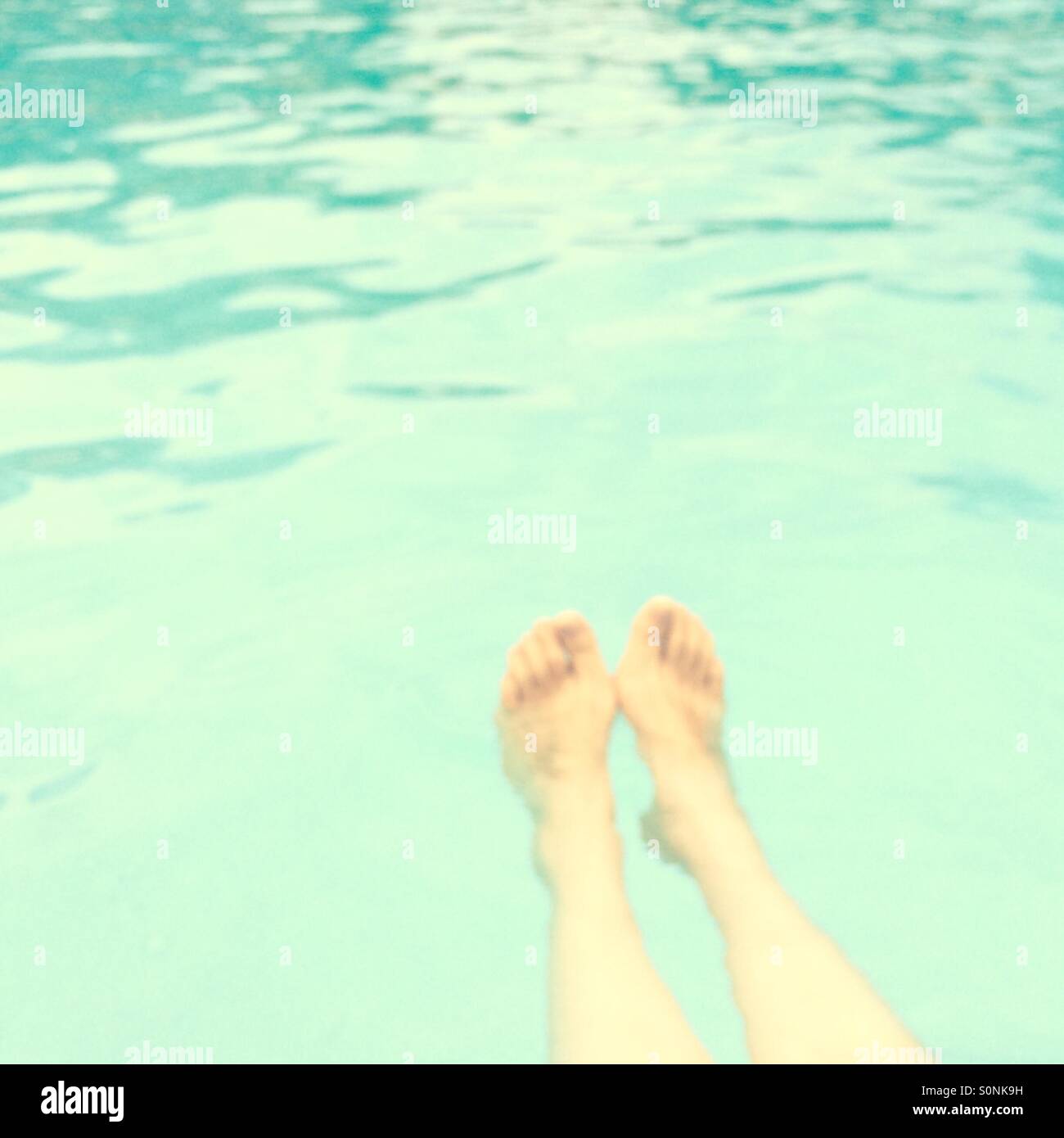 Out of focus female legs in a swimming pool. Stock Photo