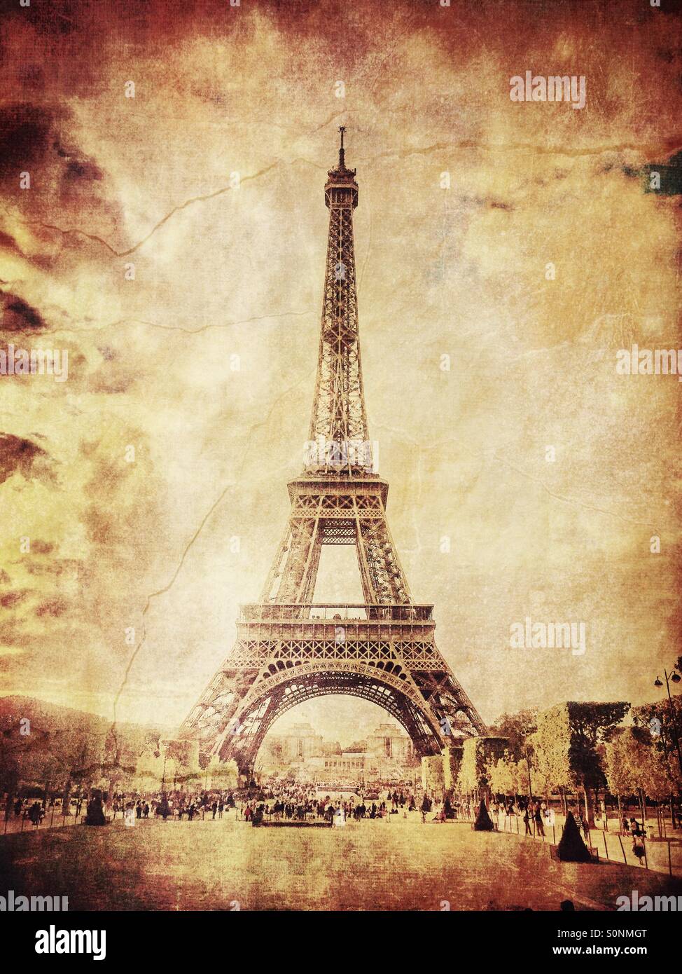 View of Eiffel Tower from Champs de Mars in Paris, France. Aged sepia tones and vintage paper texture overlay. Stock Photo