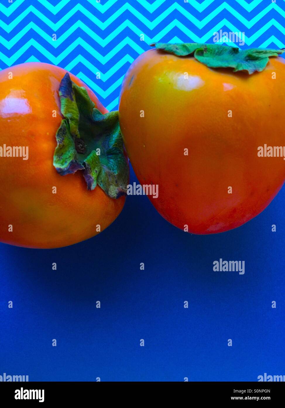 Persimmons on blue and chevron background - Smartphone Captured Stock Image