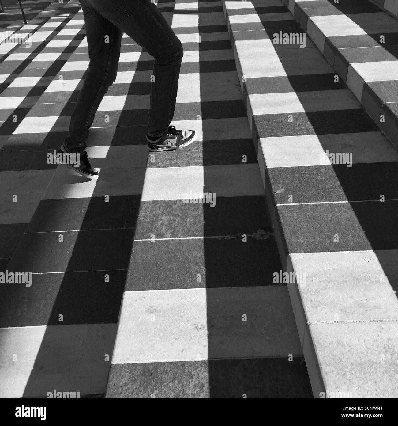 Man in tennis shoes climbs shadowy stairs - Smartphone Captured Stock Image