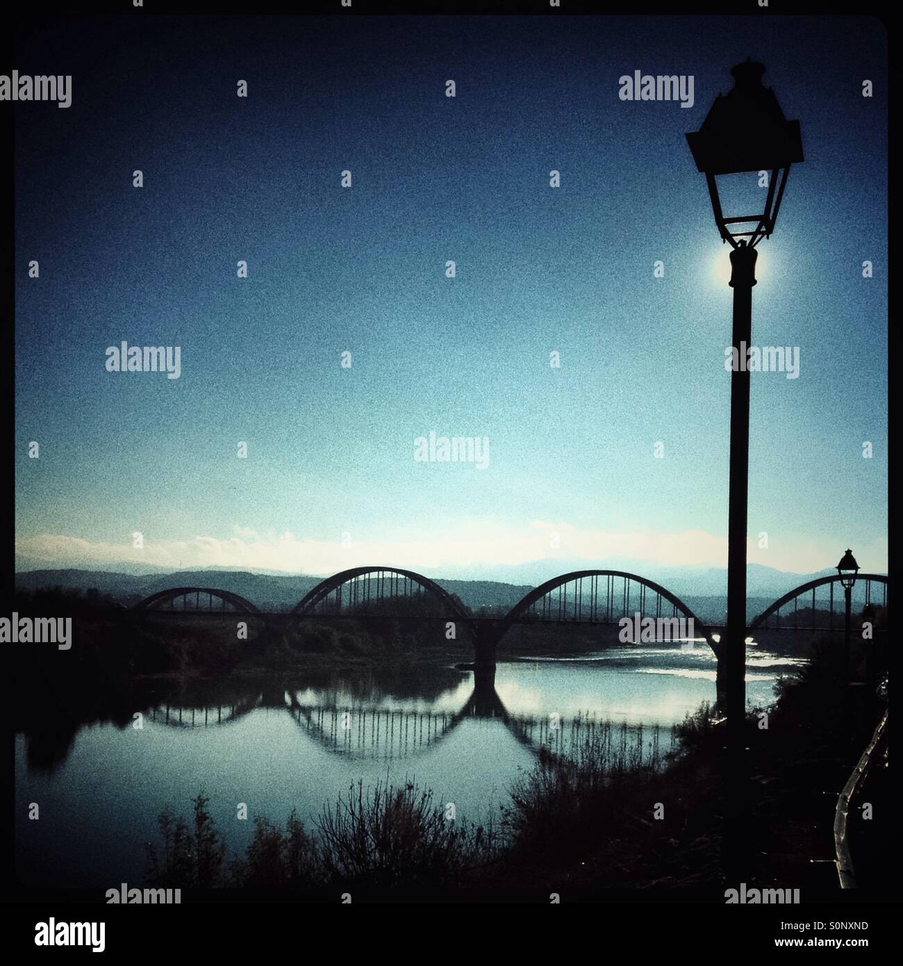 Traditional street lamp along the river walkway, with a view of the bridge, Mora d'Ebre, Spain. - Smartphone Captured Stock Image Traditional street lamp along the river walkway, with a view of the bridge, Mora d'Ebre, Spain. - Smartphone Captured Stock Image