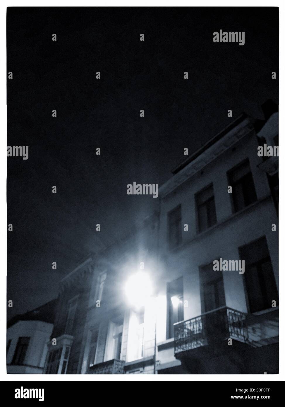 Brilliant streetlight against homes during a winter night. - Smartphone Captured Stock Image