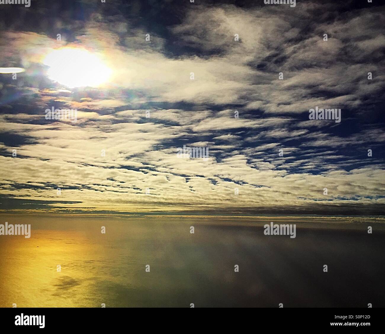Reflection on the ocean and clouds from airplane window at 37000 feet - Smartphone Captured Stock Image