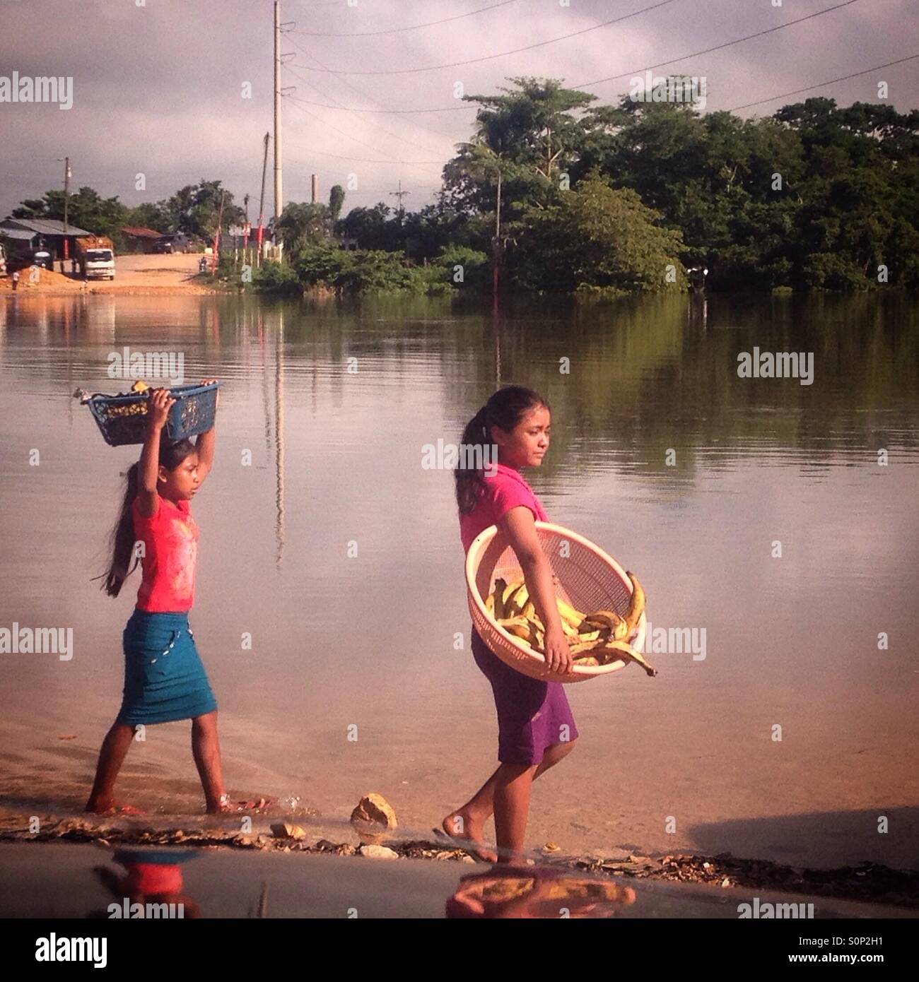 Two Mayan girls carry fruit in the river cross of Sayaxche, Peten, Guatemala Stock Photo
