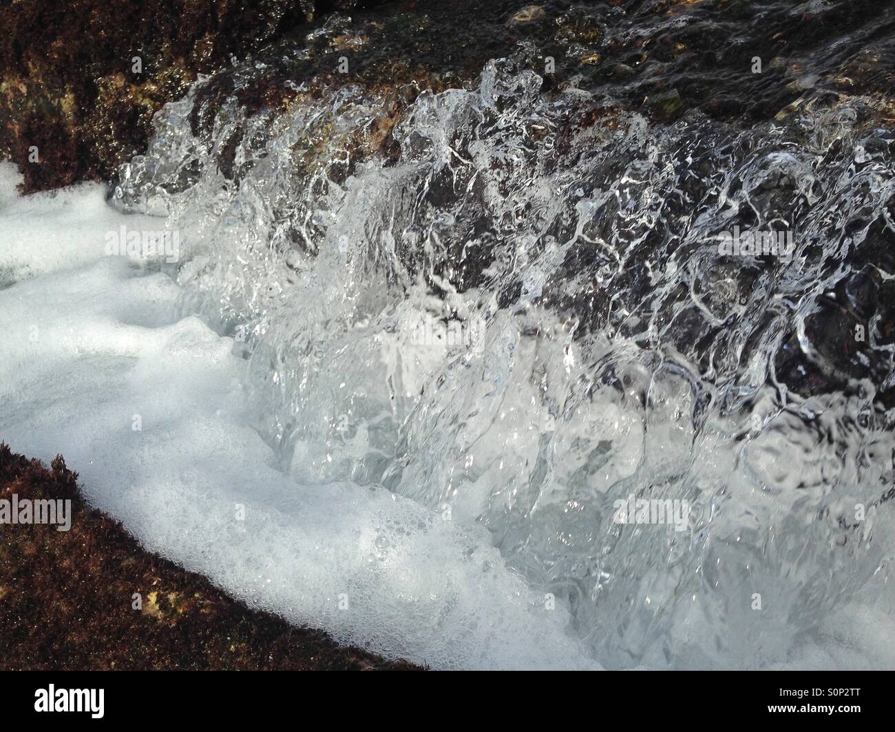 iPhone on a selfie stick capturing sea water crashing over a rock - Smartphone Captured Stock Image