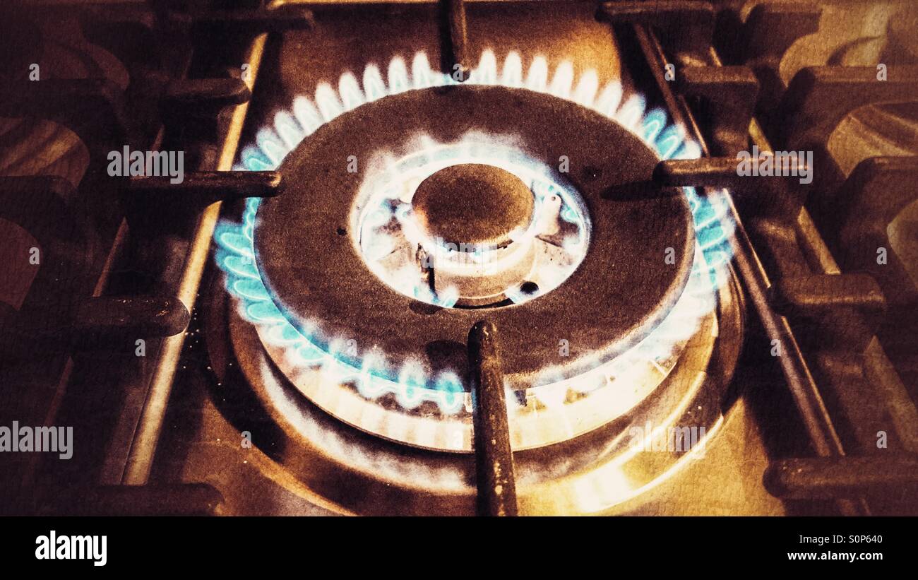 Double gas ring on a hob, lit and burning with a blue flame, in a vintage, grainy finish - Smartphone Captured Stock Image