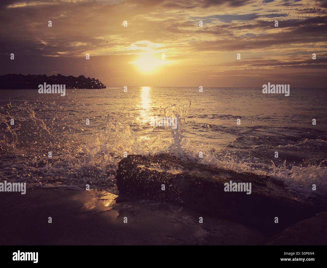 Wave spray over a rock at sunset - Smartphone Captured Stock Image