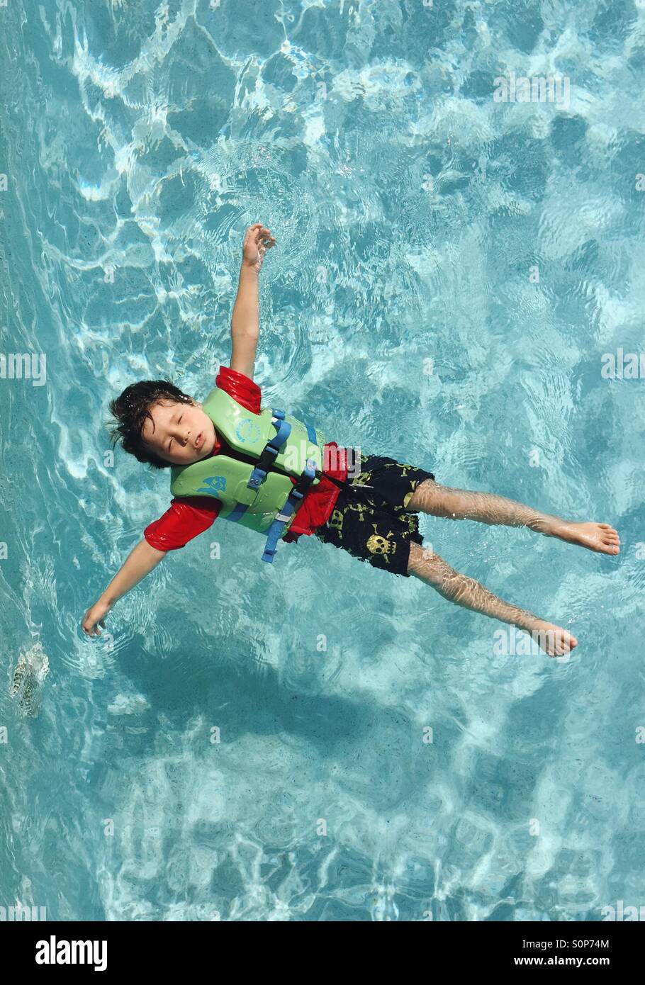 Boy floating in water in swimming pool. Stock Photo