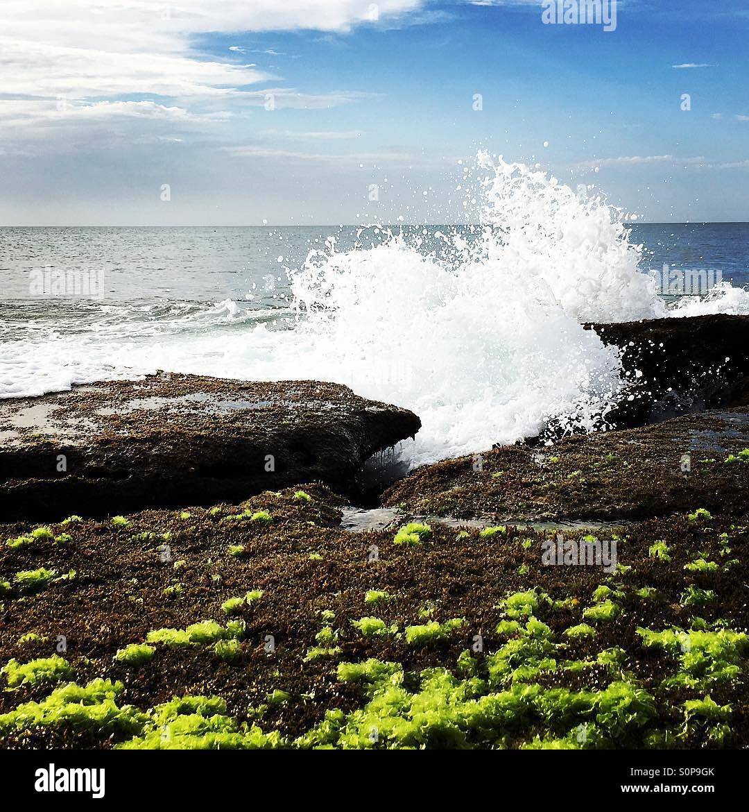 Crashing waves against rocks with blue skies - Smartphone Captured Stock Image