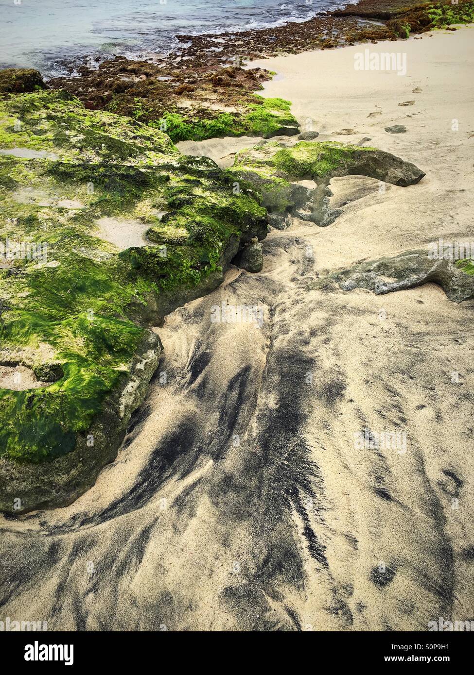 Volcanic black and golden sand mixed due to movement of tidal sea water - Smartphone Captured Stock Image