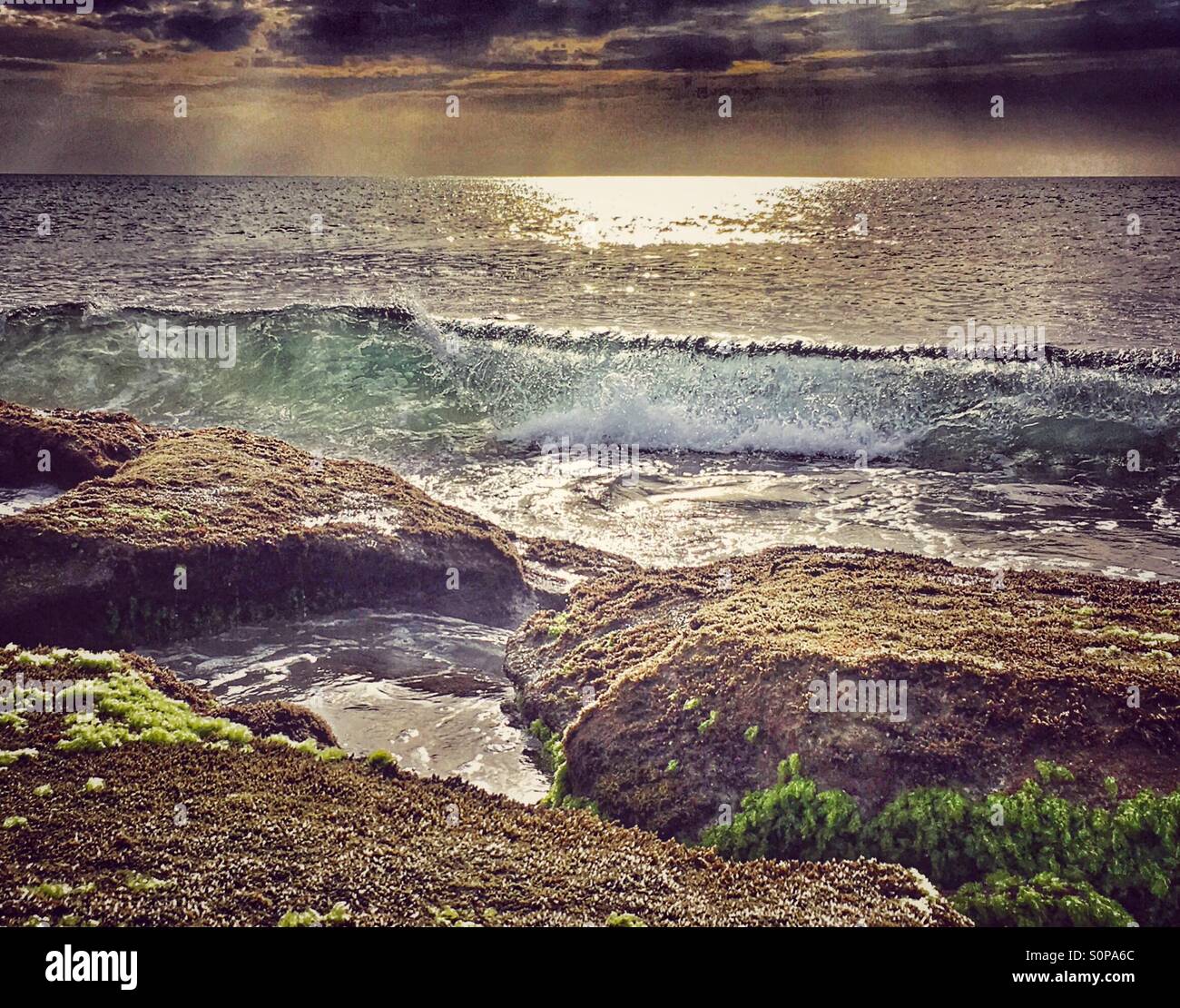 Waves barrel breaking just before rocks - Smartphone Captured Stock Image