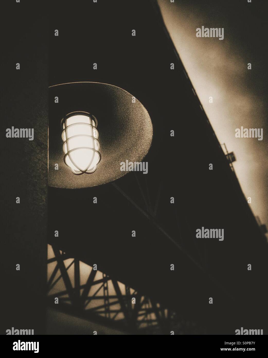 Outdoor light bulb underneath a city bridge with dark and scary atmosphere. - Smartphone Captured Stock Image