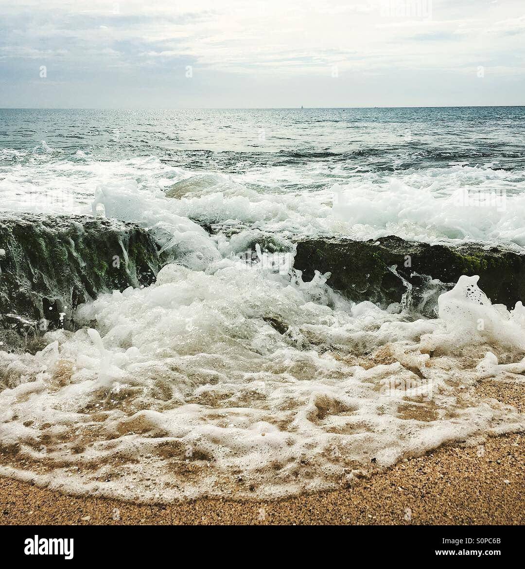 Incoming tide with wave rushing over rocks - Smartphone Captured Stock Image