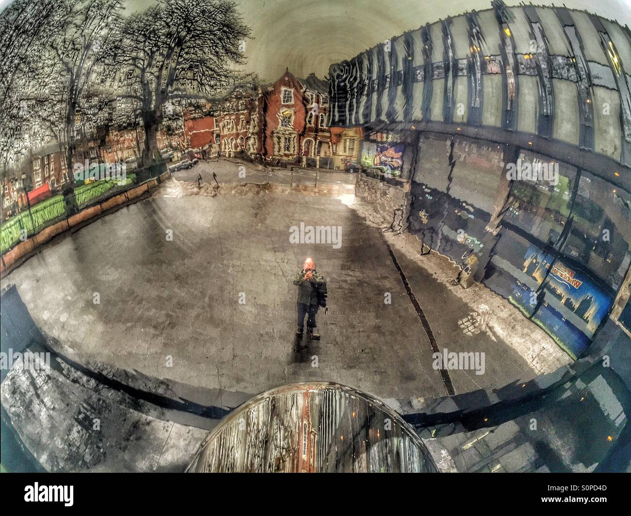 Man reflected in sky mirror in Nottingham. (Model release can be made available as subject is the photographer) Stock Photo