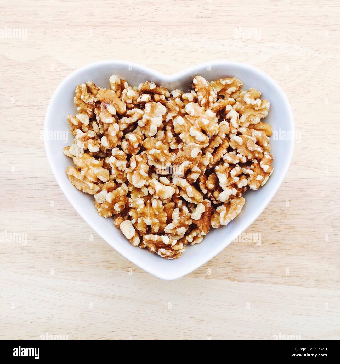 Walnuts in white heart shaped bowl Stock Photo