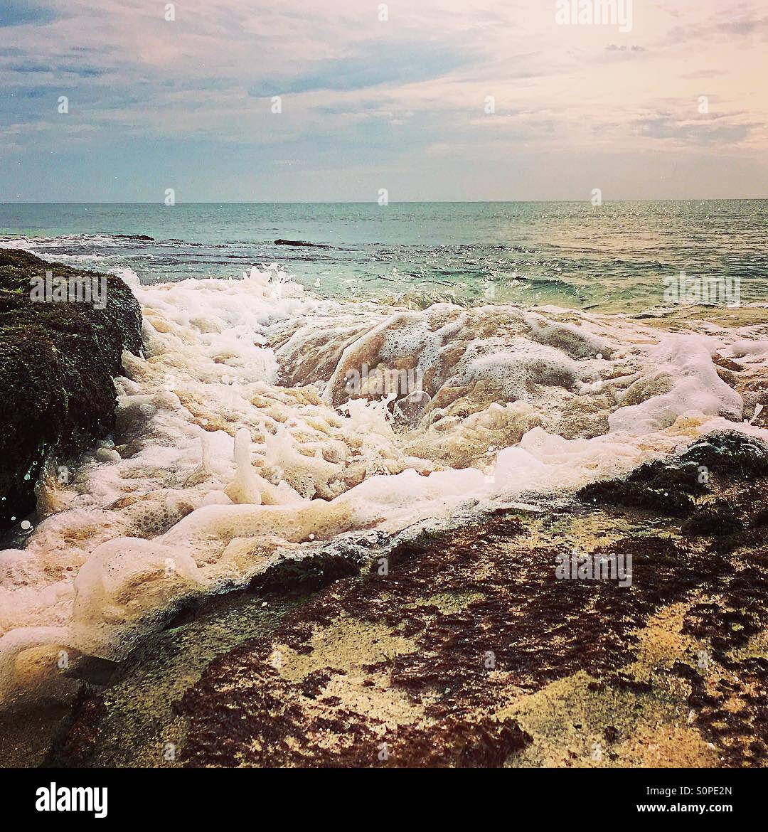 Incoming tide as the waves rush past a small gap in the rocks - Smartphone Captured Stock Image