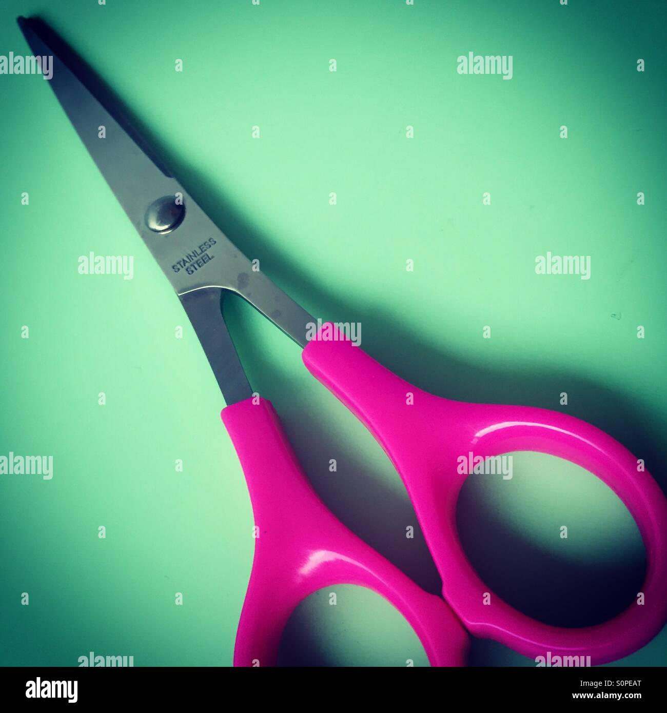 Pink handled craft scissors closeup against a green background - Smartphone Captured Stock Image