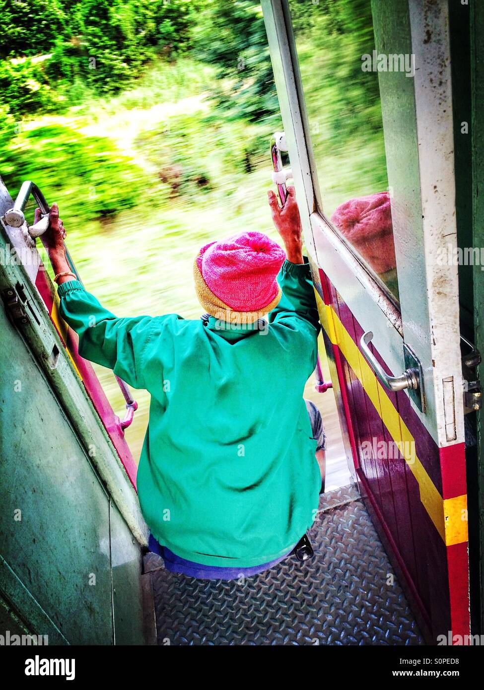 Passenger sitting by the door of a moving train in Bangkok, Thailand - Smartphone Captured Stock Image