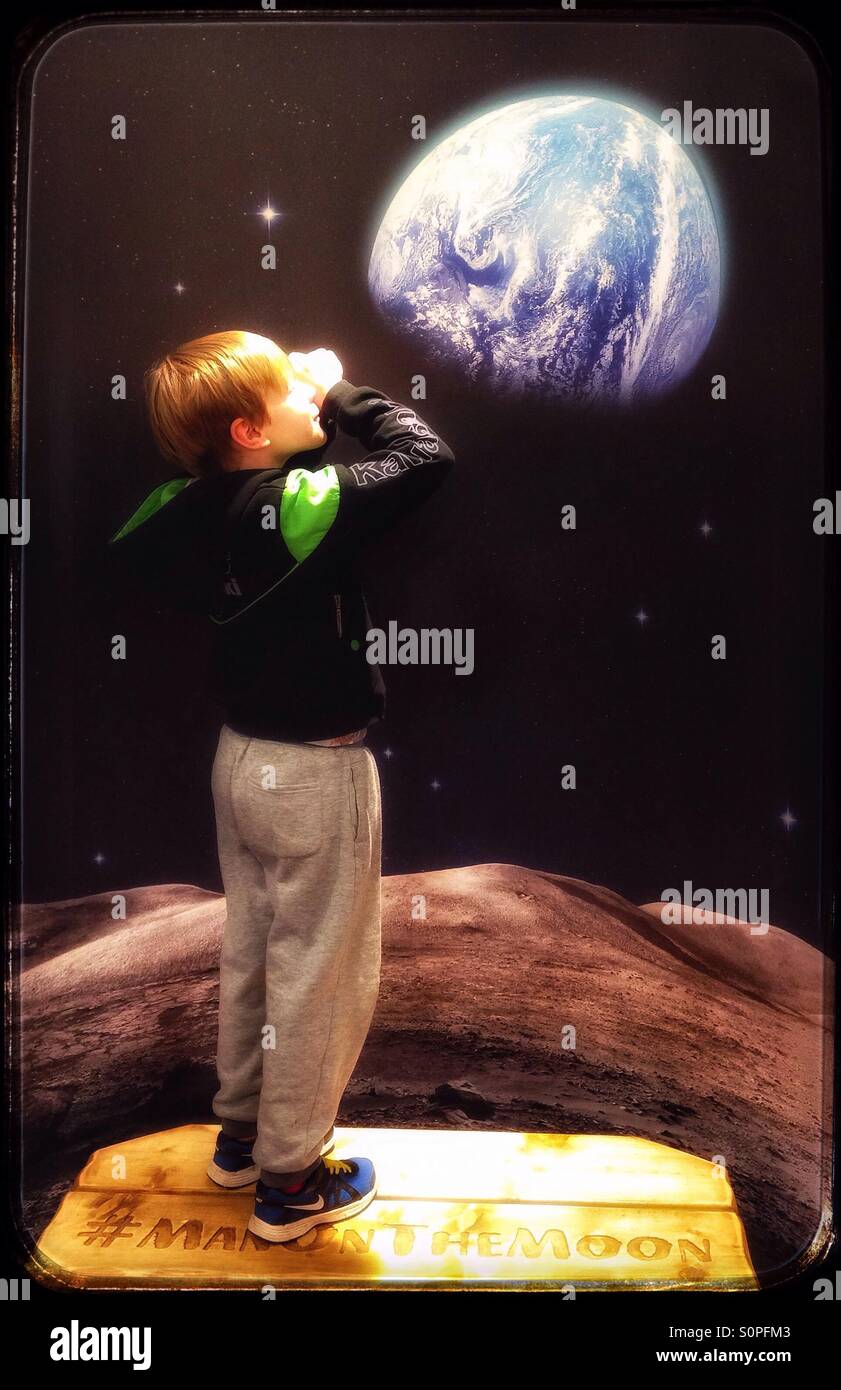 Boy on the moon looking at the earth. Stock Photo