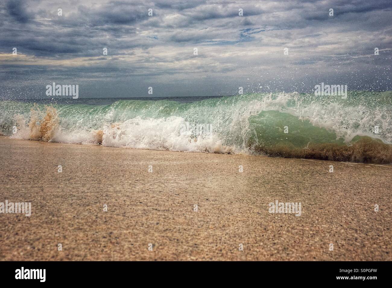 Barreling wave onto a sandy beach - Smartphone Captured Stock Image