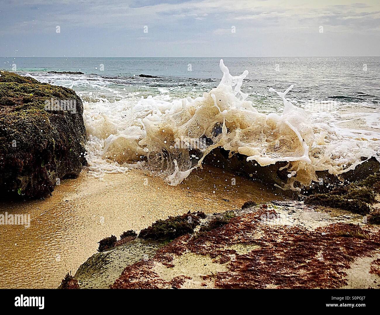Incoming tide with waves crashing over rocks - Smartphone Captured Stock Image