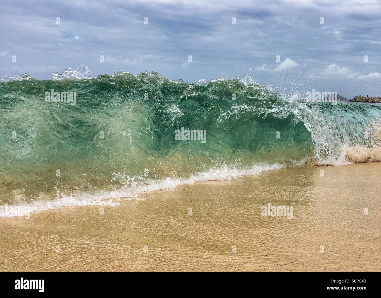 Barreling wave onto a sandy beach - Smartphone Captured Stock Image