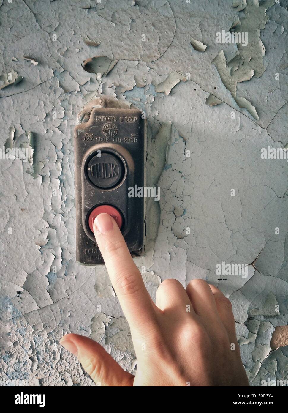 Hand push red button on the wall with cracked paint. - Smartphone Captured Stock Image