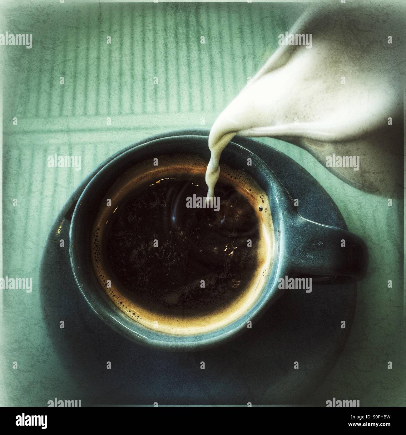Pouring milk into black coffee. - Smartphone Captured Stock Image