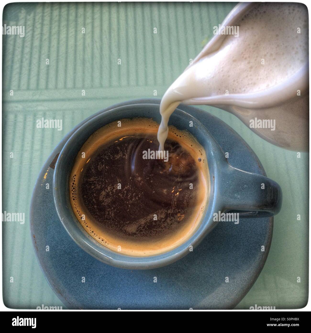 Adding milk to black coffee. - Smartphone Captured Stock Image
