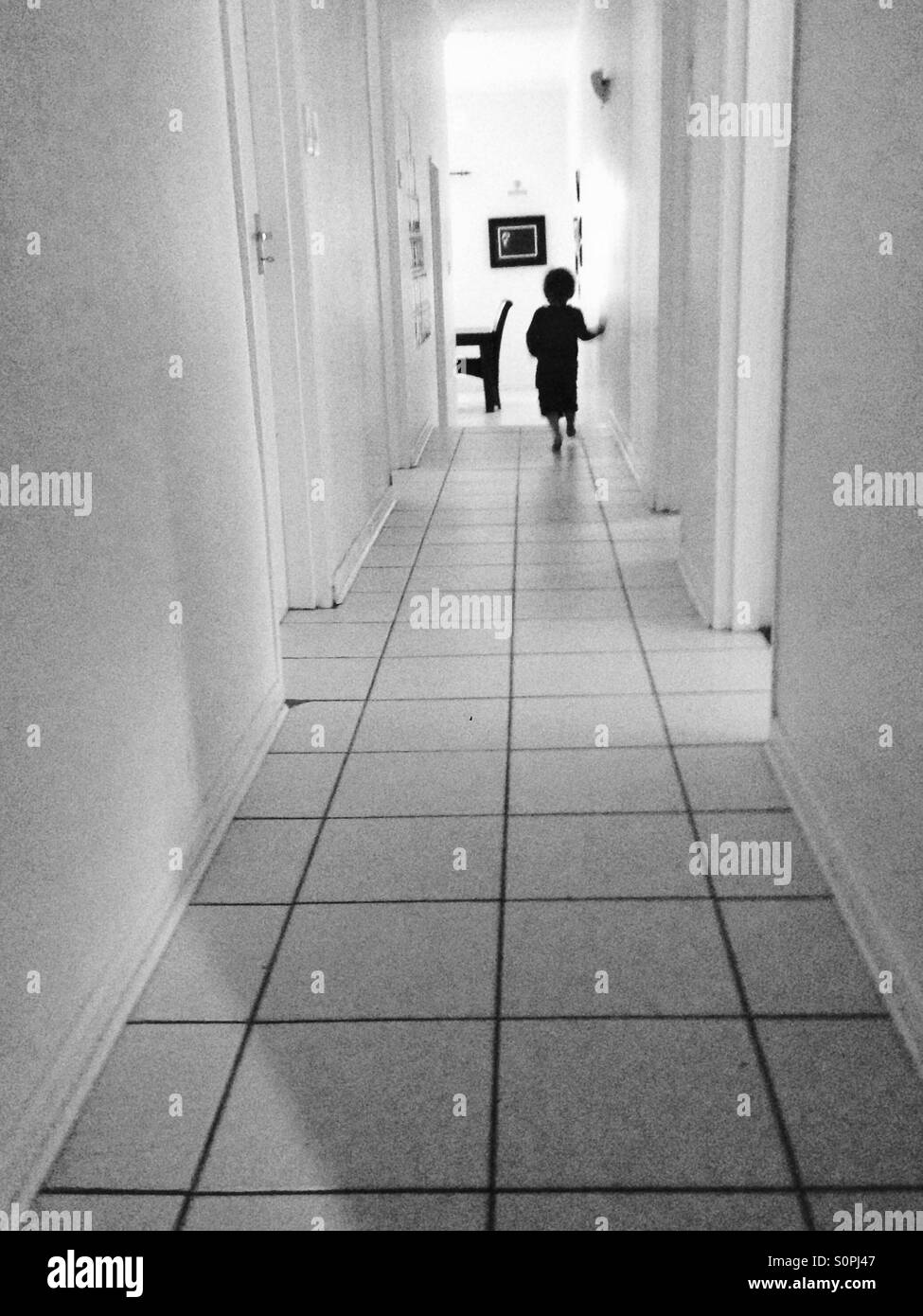 Boy walks down corridor in house Stock Photo
