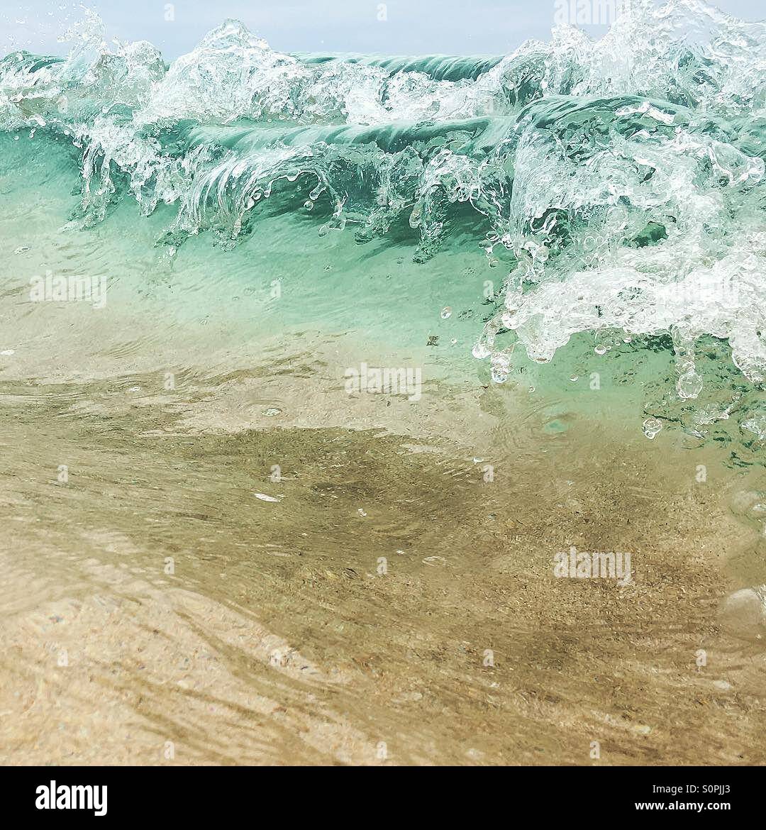 Close up of a wave breaking with the sandy floor seen through the bottom of the wave - Smartphone Captured Stock Image