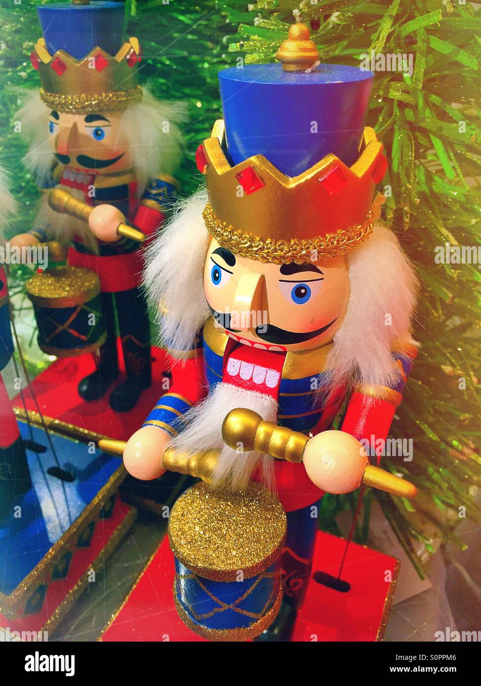 Holiday nutcracker ornament plays a toy drum on a Christmas tree. - Smartphone Captured Stock Image