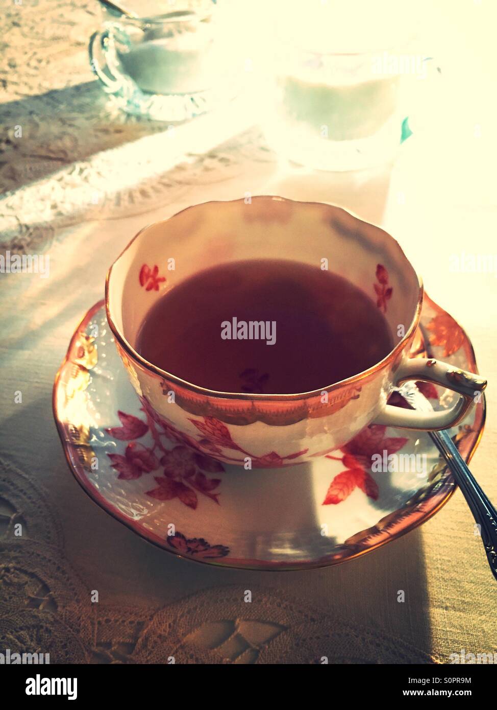 Cup and saucer is lit by the early morning sunlight through the kitchen window. - Smartphone Captured Stock Image