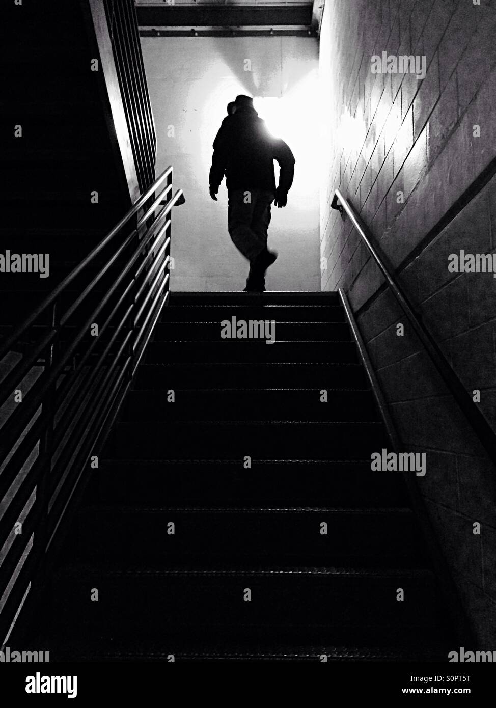 Man with hat turning at top of dark stairs - Smartphone Captured Stock Image
