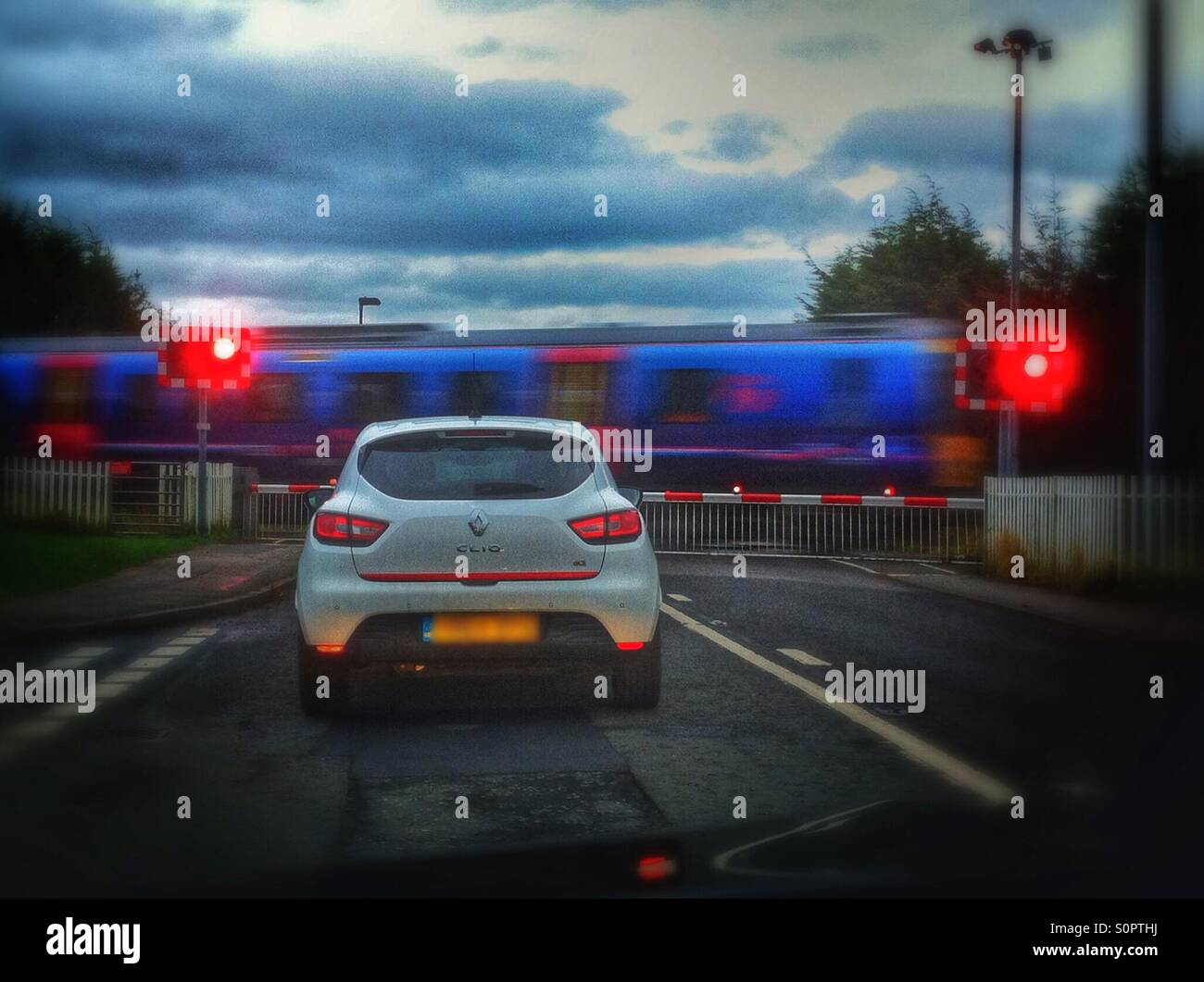 Cars waiting for train to pass at level crossing England UK United Kingdom GB Great Britain - Smartphone Captured Stock Image
